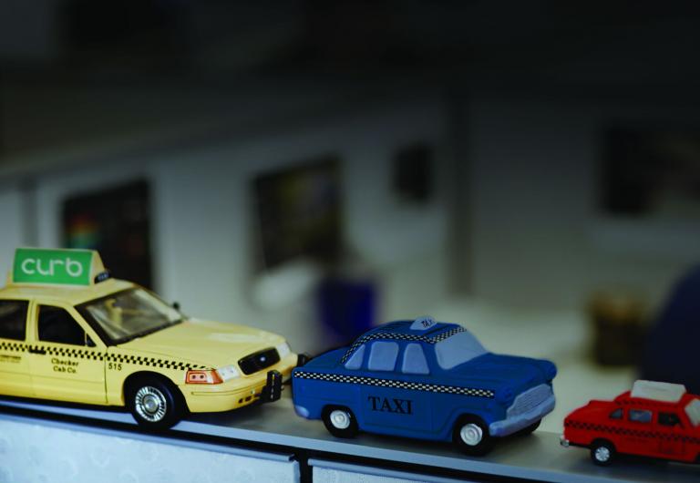 Three toy taxis of alternate sizes and colors.